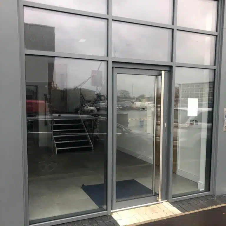 A photo of a glass shop front and a door with bar pull handle